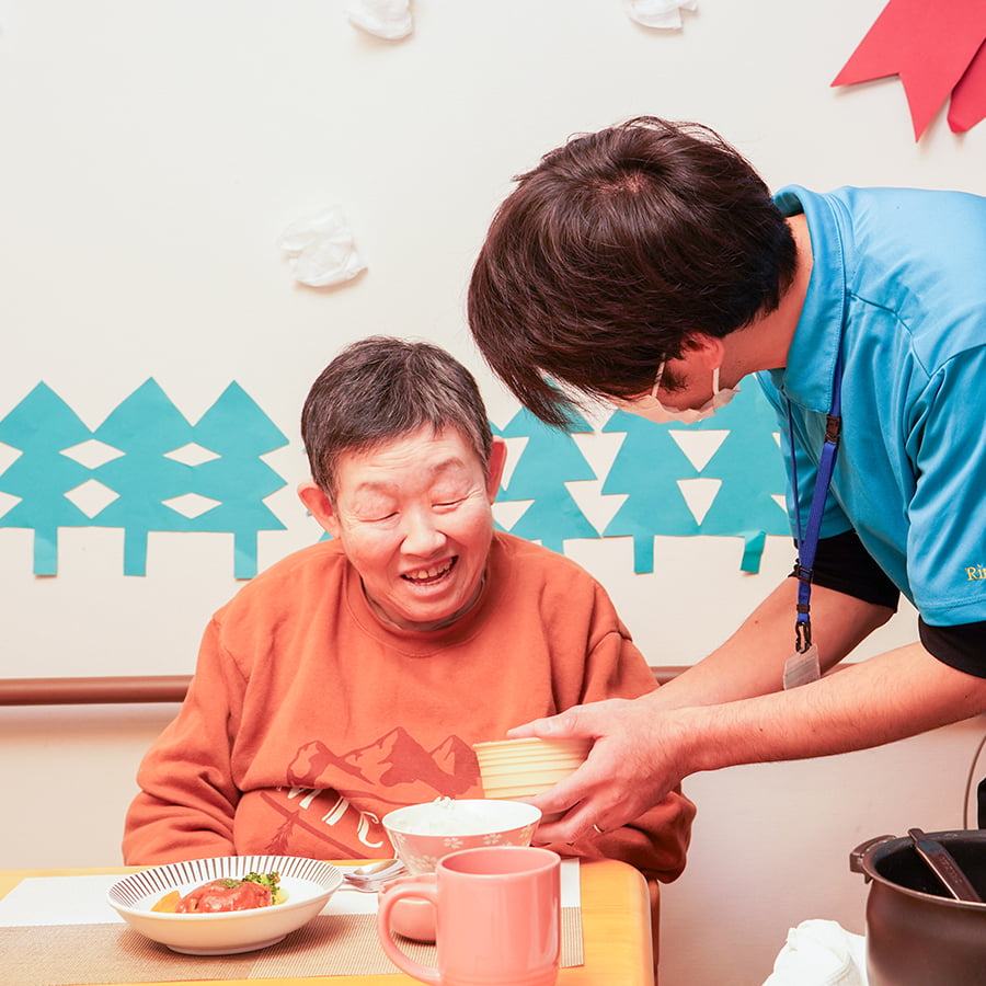 介護職員が利用者さんに食事を提供している写真