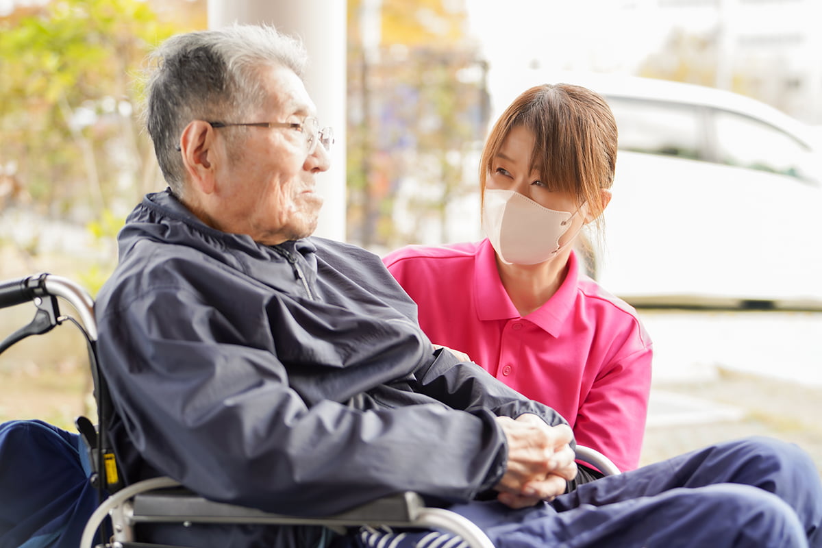 車椅子の男性と話をする介護士